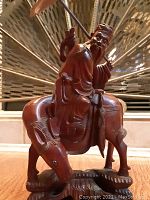 Front angle view of the rosewood carved figurine showing the elderly man holding an umbrella while sitting on the horse.
