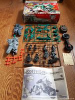 Top view of the laid out model kit components including sprues, wheels, and parts with the box in the background.