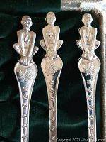 Three silver nickel souvenir Cubs spoons featuring boy figurines on handles with leaf and paw print design details.