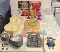 Photo showing gelatin molds, pans, plastic molds, colorful jelly molds, and a decorative towel on a table.