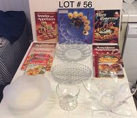 Full lot overview including all dishes, bowls, and 7 cookbooks about appetizers shown on a table with a backdrop labeled LOT 56