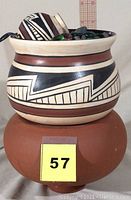 Front view of the southwestern design bowl with geometric black and white patterns and reddish-brown bands. Part of the water fountain features colored glass stones and a smaller decorated ball inside the bowl.