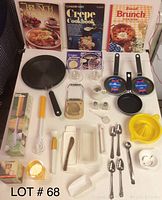 Photo of all items laid out showing skillets, cookbooks, coffee cups, juicer, beater, egg slicer, salt and pepper shakers, and spoons.