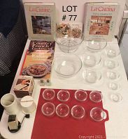 Photo showing the full assortment of 18 clear glass bowls in multiple sizes, 5 hardcover cooking books, a handheld grater, salt and pepper shakers, and a white ceramic spoon holder with a spoon on a white surface.