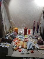 Wide view showing the assortment of candles including taper, pillar, and tea lights. Also shows a box of tea light candles and a bottle with lamp oil and wick.