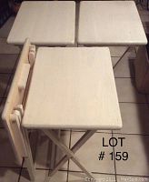 Three wooden foldable TV tray tables shown with two standing and one folded flat on the floor.