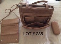 Top view of open brown leather handbag showing multiple inside compartments and card slots, along with the matching wallet and eyeglasses case placed beside it.