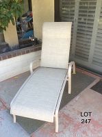 Photo of full chaise lounge showing aluminum frame and light gray fabric covering in upright position outdoors on a patio.