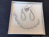 Jewelry set displayed in a box showing ring, earrings and bracelet with crystals.
