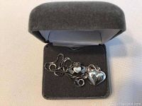 Sterling silver necklace with heart pendant displayed in a grey velvet jewelry box.