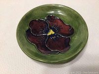 Top-down view of green Moorcroft dish showing detailed pansy flower pattern in the center.