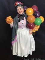 Front-facing view of Royal Doulton Biddy Penny-farthing figurine showing facial features, attire, and balloons.
