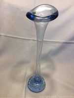 Front angle view of slender clear glass flower vase with blue-tinted oval rim and pressed bubble oval base