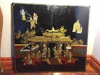 Two black lacquer panels side by side forming a continuous image of an oriental scene with figures, horses, and architecture.