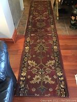Full length view of the runner rug on a hardwood floor, showing the full floral pattern and border.