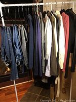 Rack with assorted women’s jeans and sweaters hung on white metal clothing rack