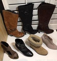 Full lot including seven pairs of ladies shoes in various styles and colors arranged in front of a window blind.