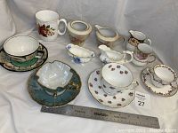 Photo showing entire china set including three full-size cups and saucers, miniature cup and saucer, tea mug, cream and sugar sets, and a ruler for scale.