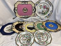 Wide view showing multiple decorative plates and the Wedgwood rectangular platter with pink center and black/cream edges, assorted colors on plates including blue, green, yellow.