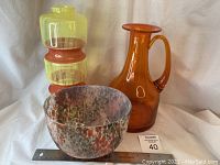 Three MSM art glass pieces together: segmented yellow-orange vase, bright orange pitcher, and mottled bowl.