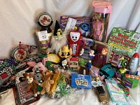 Photo showing a wide assortment of toys and collectibles including Barbie doll, candy dispensers, plush Beanie Babies, toy guns, puzzles, and other small items arranged on a white backdrop.