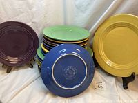 Stack of smaller and dinner plates in four colors with one blue plate shown on back with Bosco-ware maker's stamp.
