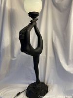 Full view of matte black figurine lamp with white globe shade against white backdrop