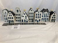 Front view of all eight porcelain Delft houses in a row with ruler