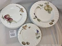 Set of 3 different plate types including side, salad, and soup bowls with natural fruit and nut illustrations on white porcelain with scalloped edges.
