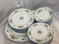 Full view of multiple plates and oval platter stacked showing floral pattern and gold trim