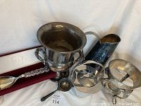 Overview of the silver and silver plate serving and drinkware items including the ice bucket, pitcher, chafing dish, teapot, and tea strainer.