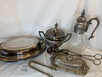 Full view of all items in the lot including coffee carafe, lidded urn, butter dish, serving platters, and tongs
