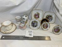 Overview photo showing all items in the lot including a cup and saucer, small decorative plates, tiny vase, and other miniature china pieces.