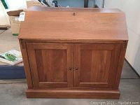 Front view of closed cherry wood drop front desk by Ethan Allen showing two panel doors and lock.