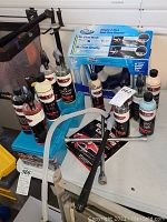 Overview of multiple bottles of car care liquids with spray bottles and a boxed item, arranged on a white surface in a garage setting.