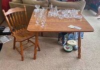 Oak drop leaf table and single matching chair, table surface with glassware on top.