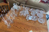 Full view of the 21 piece set arranged on a wooden table showing glasses and cut crystal dishes
