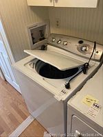 Photo of GE Profile top-loading washing machine with lid open showing the tub and power cord.