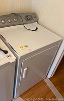 White GE Profile dryer with visible control panel and power cord on top, viewed from the front and side angles.