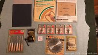 Overview of woodworking tools and accessories including sandpaper, carving tools, measuring tape, router bits, and carbide blade.
