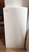 Single white rectangular shelf leaning against a wall showing a smooth, clean surface with minor marks.
