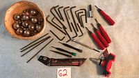 Photo showing miscellaneous tools including Allen keys, small screwdrivers, drill bits, punch, wrench tool, and basket of steel ball bearings on blue surface