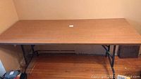 Full view of the foldable table showing the wood grain rectangular top and metal legs.