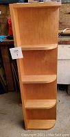 Tall light wood kitchen cabinet with three open shelves having rounded fronts