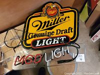 Front view of Miller Genuine Draft Light neon beer sign with broken neon letters on a clear background, electronic cords visible.