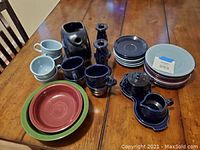 Full tea set and additional items arranged on table showing cups, saucers, plates, cream and sugar set with tray, candlesticks, and bowls.