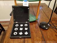 Tic-Tac-Toe game set opened displaying white X and O pieces on black felt inside a wooden box.