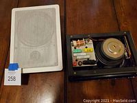 Boston in-wall speaker with grille removed showing internal components and crossover circuit board on wooden table