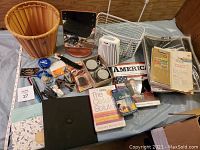 Overview photo of all items included in the lot: wood basket, lighted mirror, books, office supplies, and storage items.