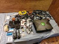 Overview of untested original Xbox console with many cables and miscellaneous electronics around it.